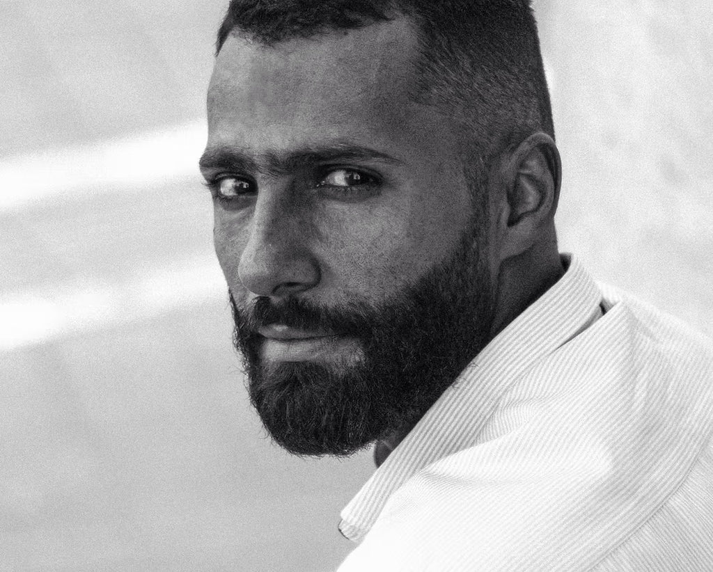 Black and white portrait of a man with a beard wearing a light-colored shirt.